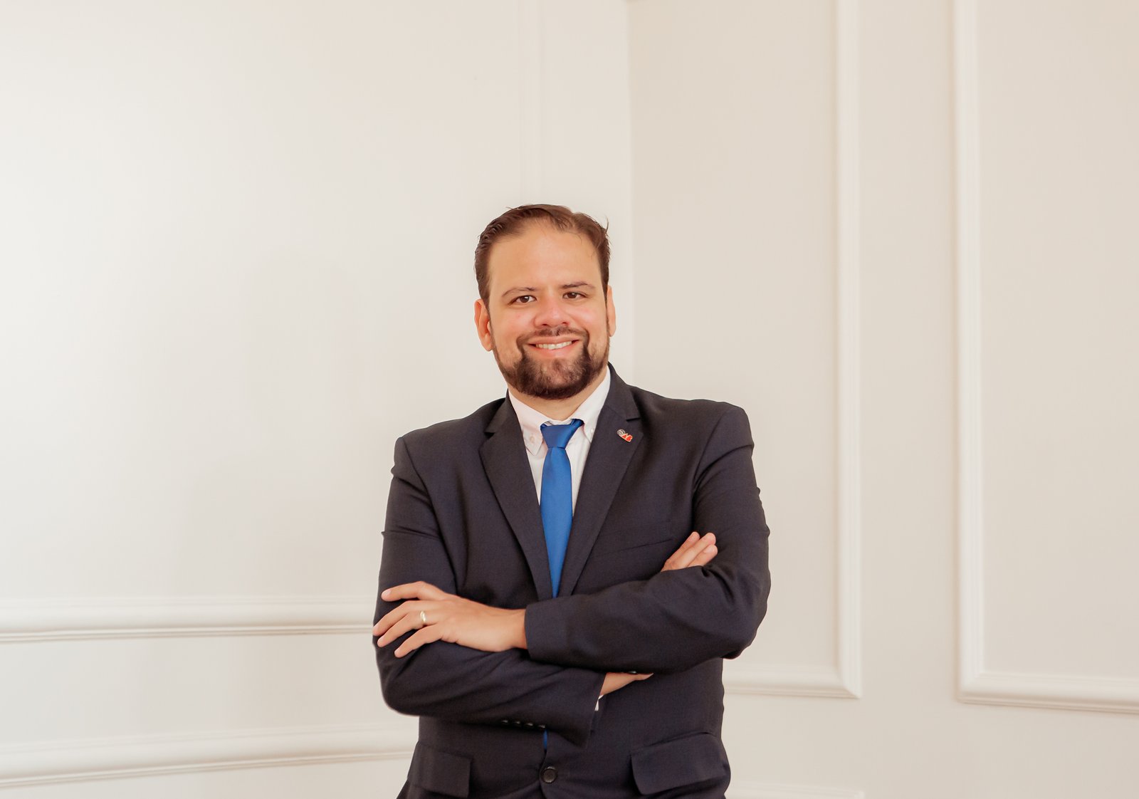 Retrato profissional do advogado, de terno azul e braços cruzados